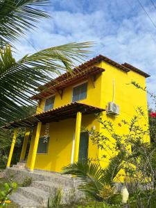 a yellow house with a palm tree in front of it at Ilha de Boipeba Casa com 2 quartos com ar condicionado no 1ºandar in Cayru