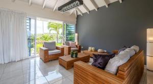 a living room with wooden couches and a large window at Villa Star Beach - Private pool and sea view! in Willemstad