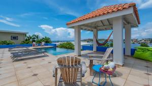a patio with chairs and a gazebo and a pool at Villa Star Beach - Private pool and sea view! in Willemstad