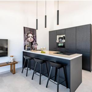 een keuken met zwarte kasten en een eiland met barkrukken bij Penthouse Mesa Bonita in Jan Thiel