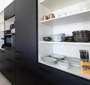 een keuken met zwarte kasten met borden en keukengerei bij Penthouse Mesa Bonita in Jan Thiel
