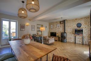 Salignac EyviguesMaison T3 tout confort et spa Le Clos des Pierres的客厅配有木桌和砖墙