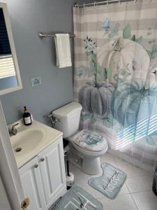a bathroom with a toilet and a shower curtain at Signature Suite in Orlando +2 photos