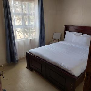 a bedroom with a large bed with a window at Crown Accommodation Narok in Narok