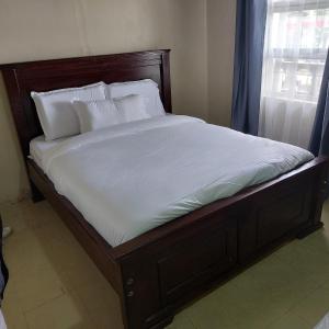 a bed with white sheets and pillows in a bedroom at Crown Accommodation Narok in Narok