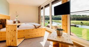 a bedroom with a bed and a large window at Erlebnishotel "Zur Schiffsmühle" GmbH in Höfgen