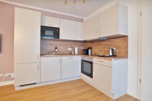 eine weiße Küche mit weißen Schränken und Holzböden in der Unterkunft Premium Apartments I home2share in Osnabrück