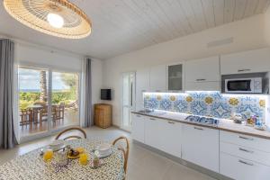 une cuisine avec des armoires blanches et une table avec des chaises dans l'établissement I Mirti - Home Holiday, à Marina di Mancaversa