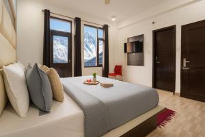 ダラムシャーラーにあるOm Eco Staysのベッドルーム1室(山々を背景に大型ベッド1台付)