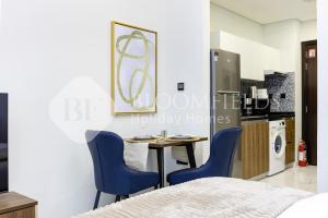 Habitación con mesa y 2 sillas azules en Bloomfields Elegant Pool View Stu The Gate, en Abu Dhabi Intl