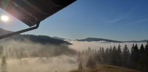 a view of a foggy valley with trees and the sun at Bucovina Sky View in Gura Humorului
