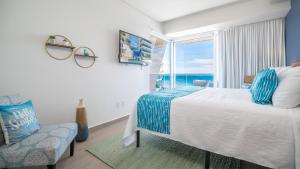 a bedroom with a bed and a window with the ocean at Encantame Towers Verano 1401 in Playa Encanto +21 photos