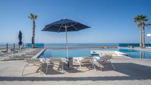 a group of chairs and an umbrella next to a pool at Encantame Towers Viento 304 in Playa Encanto