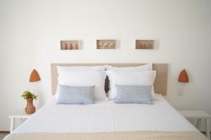 een witte slaapkamer met een wit bed met blauwe kussens bij Casa Aia in Aracaju