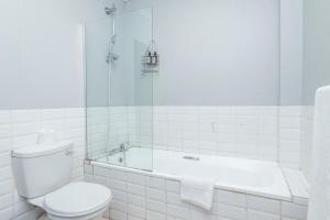 a white bathroom with a toilet and a bath tub at City Oasis Suite Cape Town in Cape Town