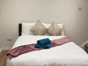 Crown Residency London في لندن: سرير ابيض وعليه قبعة زرقاء +3 صور