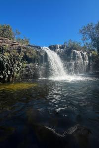 a waterfall in the middle of a body of water at Chalé Moinho Localização Privilegiada em Carrancas - MG in Carrancas