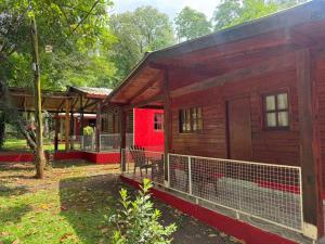a wooden cabin with a red wall in a park at Refugios y Cabañas BAHIA in Puerto Iguazú