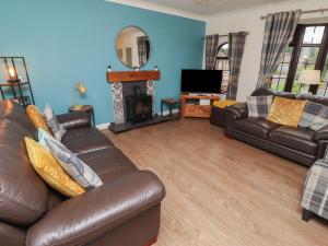 a living room with a leather couch and a television at Nobles Nook in Seahouses