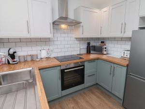 a kitchen with blue cabinets and white appliances at Nobles Nook in Seahouses