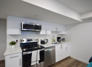 a kitchen with white cabinets and a stove top oven at Guest Suite with Private Entry in Calgary in Calgary +7 photos