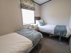 two beds in a small room with a window at Heather William Lodge in Woodhall Spa