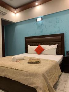 ein Schlafzimmer mit einem großen Bett mit einer blauen Wand in der Unterkunft GOHO Rooms Badar in Karatschi