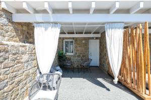 a patio with white curtains and a stone wall at Double M Adults Only in Ano Mera +5 photos
