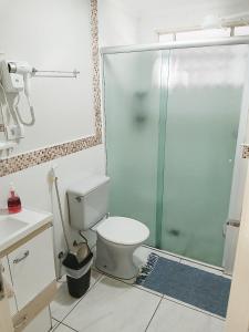 a bathroom with a toilet and a glass shower at Apartamento 222 Pé na Praça 1 vaga Garagem 7 hóspedes in Poços de Caldas +17 photos