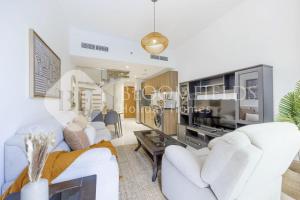 Una sala de estar con muebles blancos y un televisor grande. en Bloomfields Elegance 1br in Oasis Masdar, en Abu Dabi