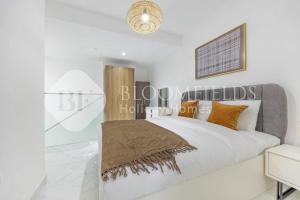 1 dormitorio con paredes blancas y 1 cama con almohadas de color naranja en Bloomfields Elegance 1br in Oasis Masdar, en Abu Dabi 5 fotos más