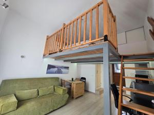 a living room with a green couch and a staircase at Studio cosy avec mezzanine & parking 2min Walibi in Les Avenières
