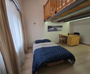 a bedroom with a bed and a table with a desk at Studio cosy avec mezzanine & parking 2min Walibi in Les Avenières +4 photos
