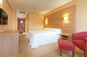 une chambre d'hôtel avec un lit blanc et une chaise rouge dans l'établissement Hotel Puertollano, à Puertollano