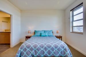 a bedroom with a bed with a blue comforter and a window at Ocean View of Rocky Shore! Yachats! Shorely Blessed in Yachats +23 photos