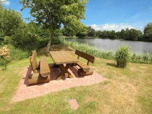une table de pique-nique et un banc en bois à côté d'un lac dans l'établissement Apartment house at Kiessee, Westerholt, à Westerholt