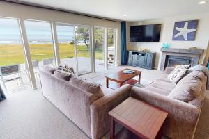 een woonkamer met een bank en een open haard bij Ocean Front, Amazing Views! Hot Tub! Sandy Seclusion in San Marine