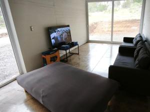 トゥンケンにあるConcrete house overlooking the ocean and beach accessのソファと薄型テレビのあるリビングルーム