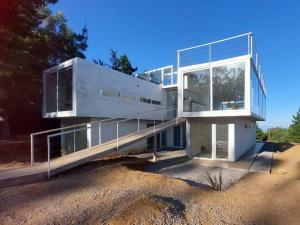 トゥンケンにあるConcrete house overlooking the ocean and beach accessの畑の上に建つガラス張りのファサードの家