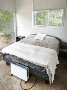 トゥンケンにあるConcrete house overlooking the ocean and beach accessのベッドと2つの窓がある寝室