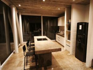 トゥンケンにあるConcrete house overlooking the ocean and beach accessのテーブルと椅子と冷蔵庫のあるキッチン