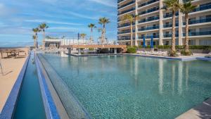 a swimming pool with palm trees and a building at Encantame Towers Viento 1002 in Playa Encanto