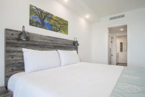 a bedroom with a white bed and a wooden headboard at Splash in The New Lazy River and Sleep In Luxury Encantame Towers Velero 2202 in Playa Encanto