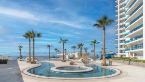 a swimming pool with palm trees and a building at Splash in The New Lazy River and Sleep In Luxury Encantame Towers Velero 2202 in Playa Encanto