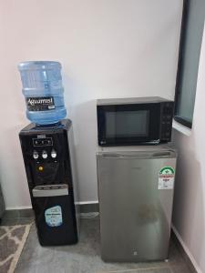 a microwave sitting on top of a refrigerator next to a water cooler at The Nest cozy stays in Kiambu