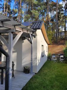 a small white building with a roof on a patio at Domek na lipowym wzgórzu in Długie