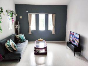 a living room with a couch and a tv at 水族館に近いゆったり別荘-Ent Terrace Okinawa in Motobu