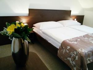 um quarto de hotel com uma cama e um vaso de flores em Penzion Dobré Hnízdo em Zlín