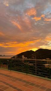 a sunset with a fence and mountains in the background at Hostel Green Light in Taganga