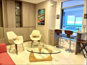 a living room with chairs and a glass table at Suite Exclusiva detrás del Decameron Punta Centinela 9F in Punta Blanca +6 photos